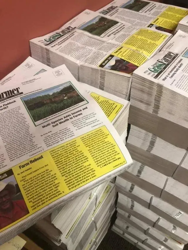 The Stockman Grass Farmer: Stacks of freshly printed Stockman Grass Farmer tabloid issues, with the masthead and front-page stories visible on the top copies.