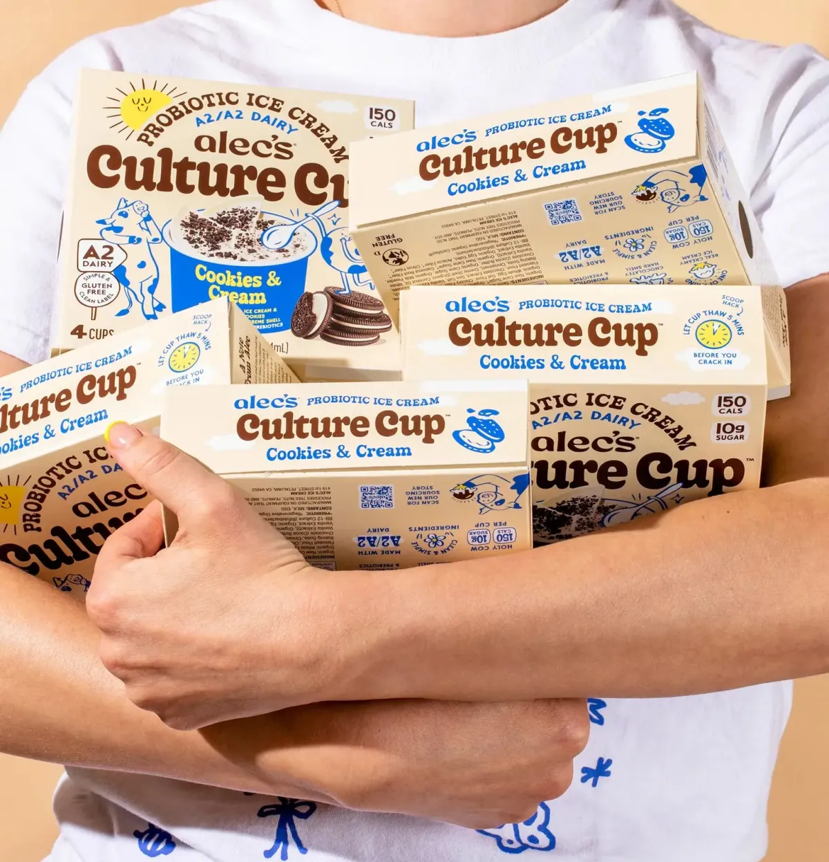 Alec's Ice Cream: A person hugging an armful of Alec's Culture Cup probiotic A2 ice cream boxes in Cookies & Cream.