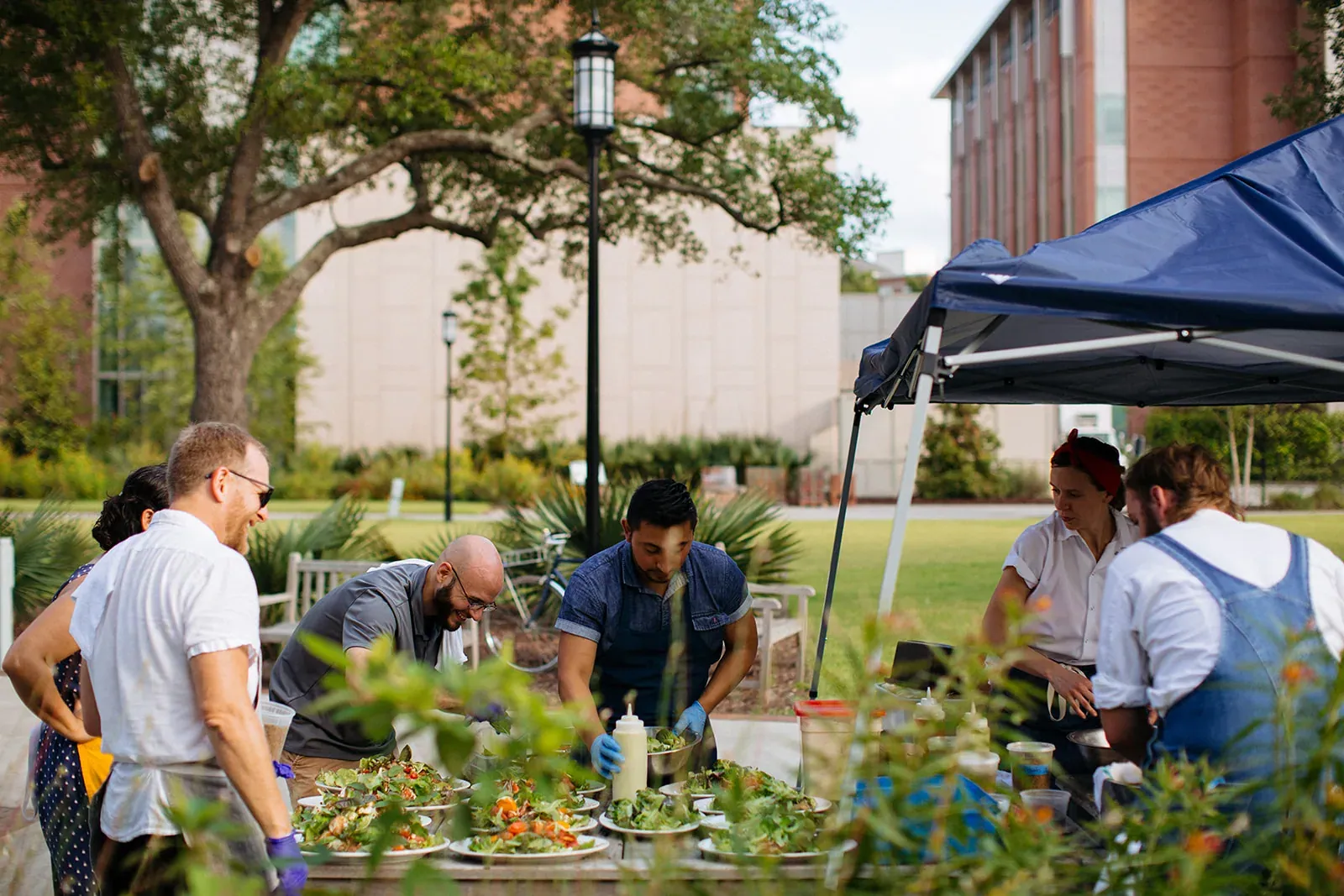 Slow Food USA: Chefs plate salads at an outdoor table under a pop-up tent during a Slow Food Ark of Taste cookout in Charleston.