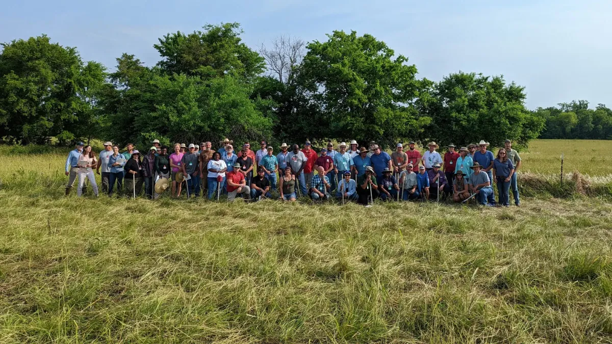 Soil Health Academy: Official channel banner: a large group of producers with name badges posing in a tall-grass pasture in front of trees during a field school.