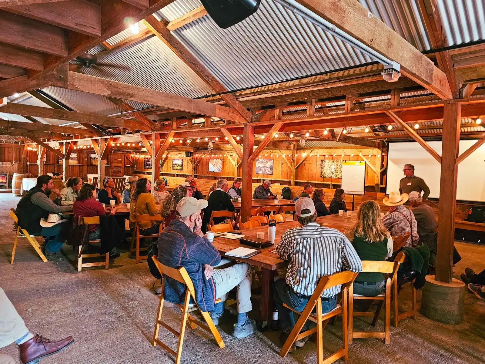 Holistic Management International: Ranchers seated at tables in a barn listen to an instructor during a Holistic Management International workshop at TomKat Ranch.