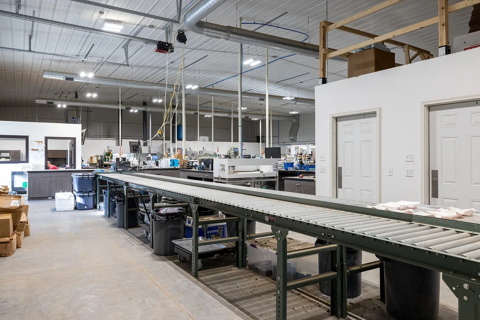 Regen Ag Lab: Interior of the Regen Ag Lab soil testing facility, with a sample conveyor in the foreground and lab benches and instruments behind.