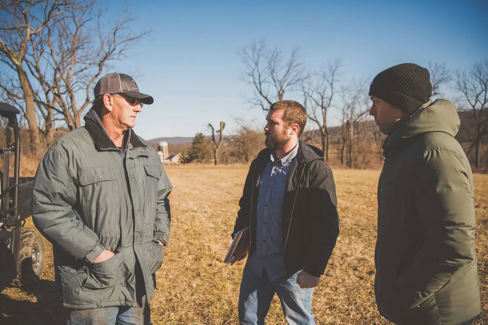 Rodale Institute Consulting: Two Rodale Institute consultants talk with a farmer in a winter pasture next to a utility vehicle.